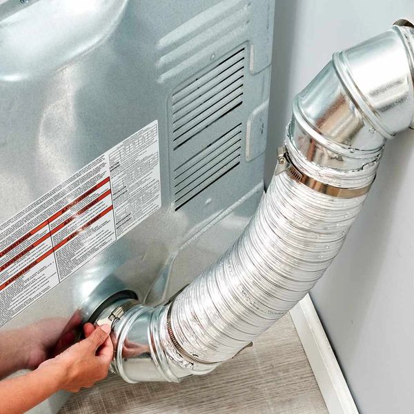 Technician removing a dryer vent from a dryer for cleaning