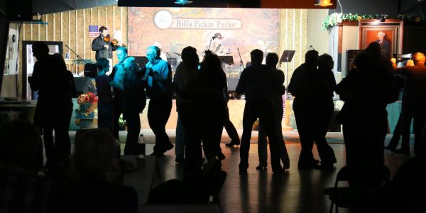 People dancing in a dimly lit hall with live music.