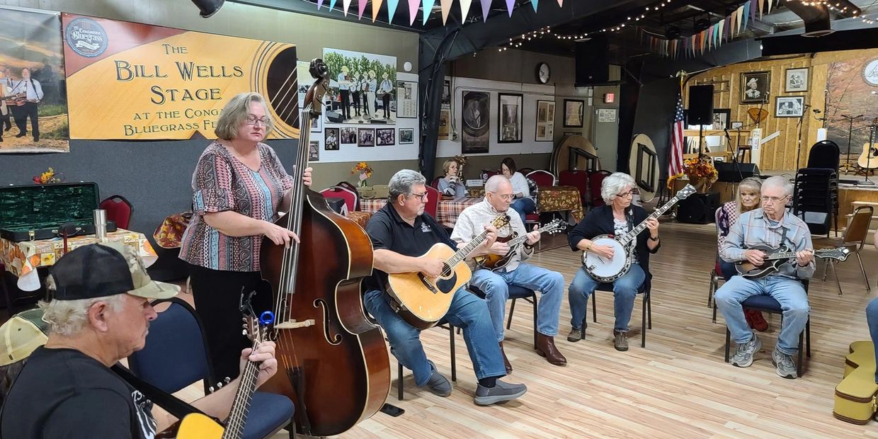Group of musicians playing bluegrass instruments in a room.