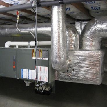 Insulated HVAC ductwork and furnace system in a basement ceiling.