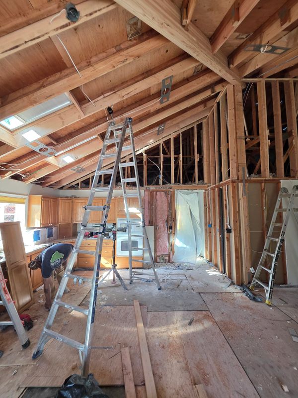 Interior of a house under renovation with exposed beams and ladders.