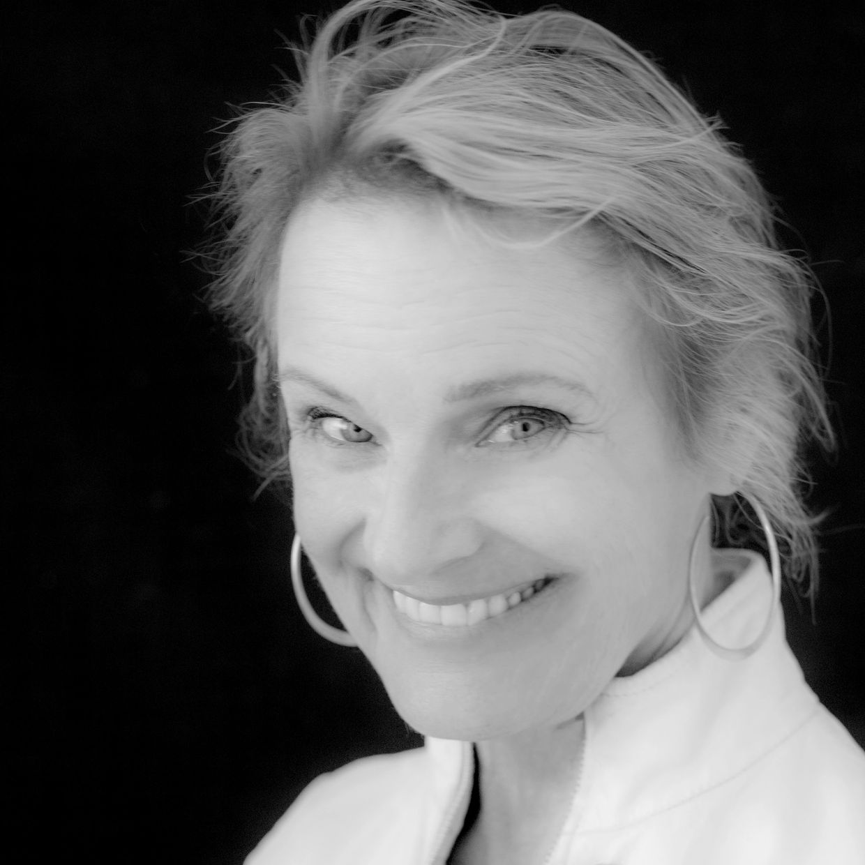 Smiling older woman with hoop earrings.