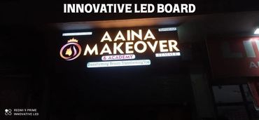 Illuminated LED signboard for Aaina Makeover & Academy at night.