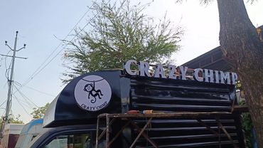Black food truck with 'CRAZY CHIMP' sign and logo of a hanging chimpanzee.