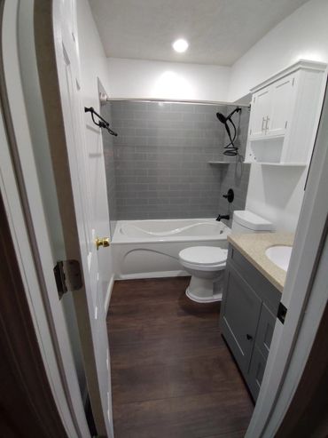 Modern bathroom with gray tiles and wooden floor.