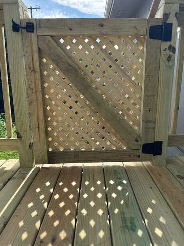 Wooden lattice gate casting diamond-shaped shadows on a wooden deck.
