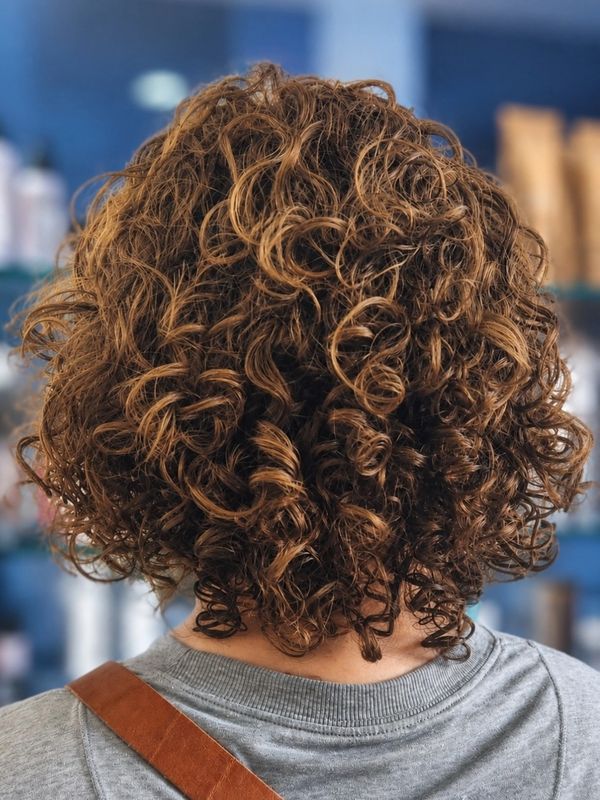 Back view of a person with short, curly brown hair.