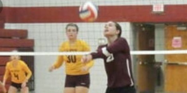Female volleyball player in maroon performing a bump pass during a game.