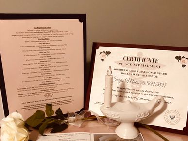 Display tribute with Nightingale poem, certificate of accomplishment, nightingale lamp, white rose.