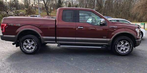 Side view of a maroon Ford F-150 pickup truck parked outdoors.
