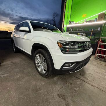 White SUV parked inside a garage with green walls and sunset outside.