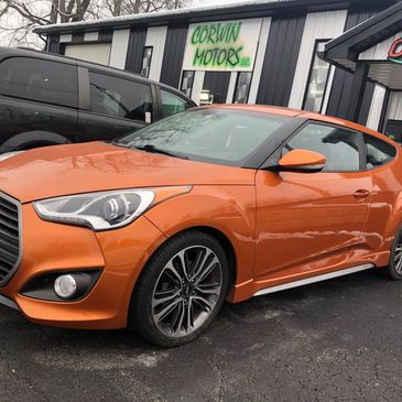 Orange Hyundai Veloster parked outside Corwin Motors dealership.