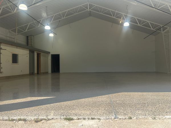 Empty industrial warehouse with polished concrete floor and overhead lights.
