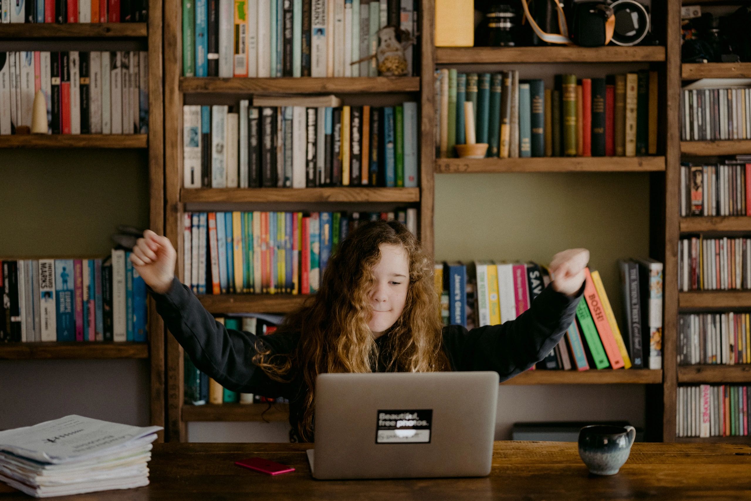 Child celebrating success at computer in a home library.