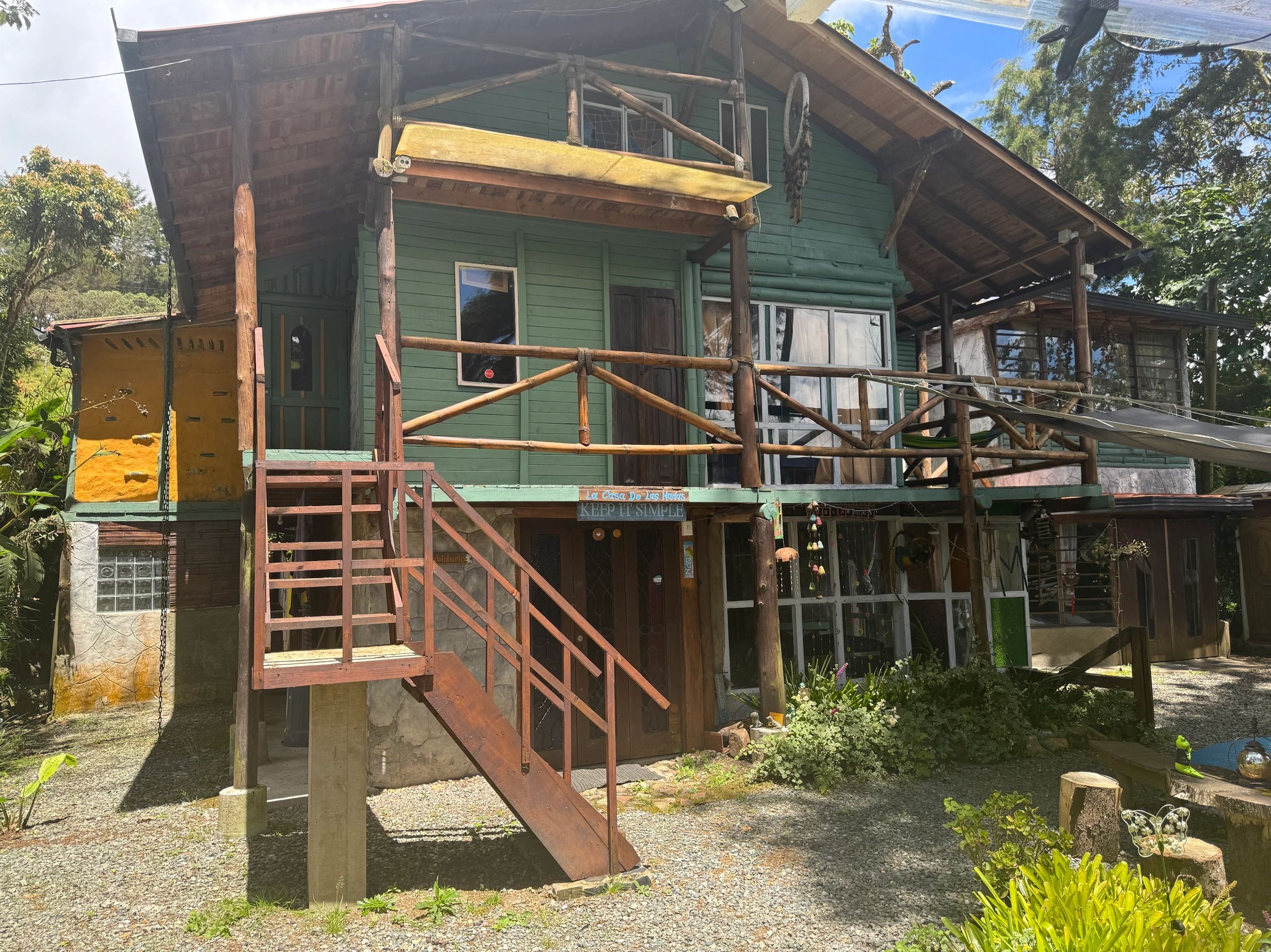 Rustic wooden house with green walls and balcony.