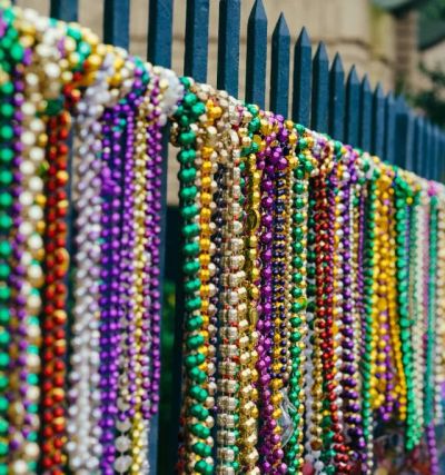 Colorful Mardi Gras beads hanging on a fence.