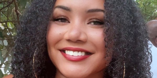 Smiling woman with curly hair and hoop earrings.