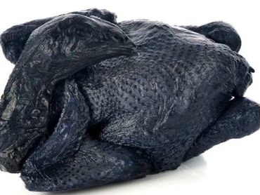 A whole black chicken with distinctive dark skin.