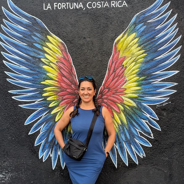 Woman posing with colorful wings mural in La Fortuna, Costa Rica.