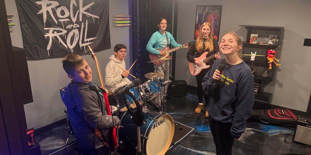 Young band practicing in a rock-themed room.