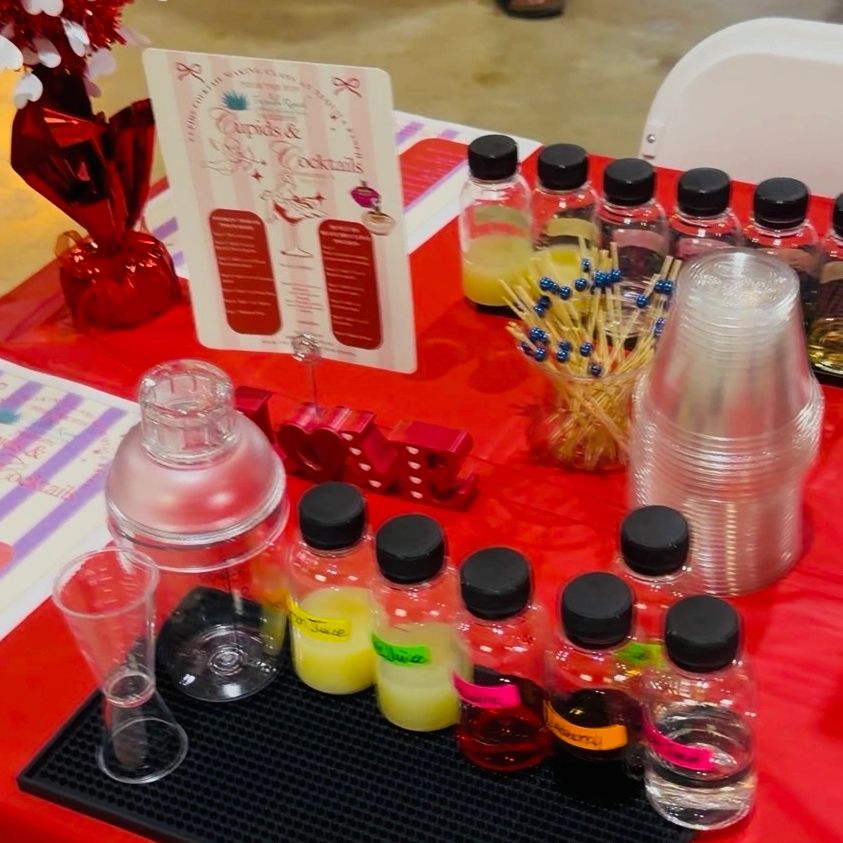 Valentine's-themed cocktail setup with labeled ingredients and red decorations.