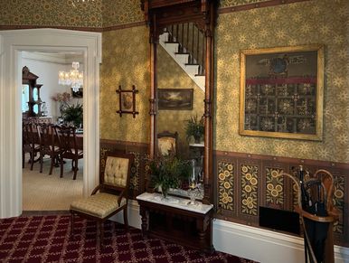 Victorian foyer with Herter Brothers wallpaper and an Eastlake-style pier mirror.