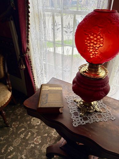 cranberry glass huricane lamp with book of Tennyson's poems