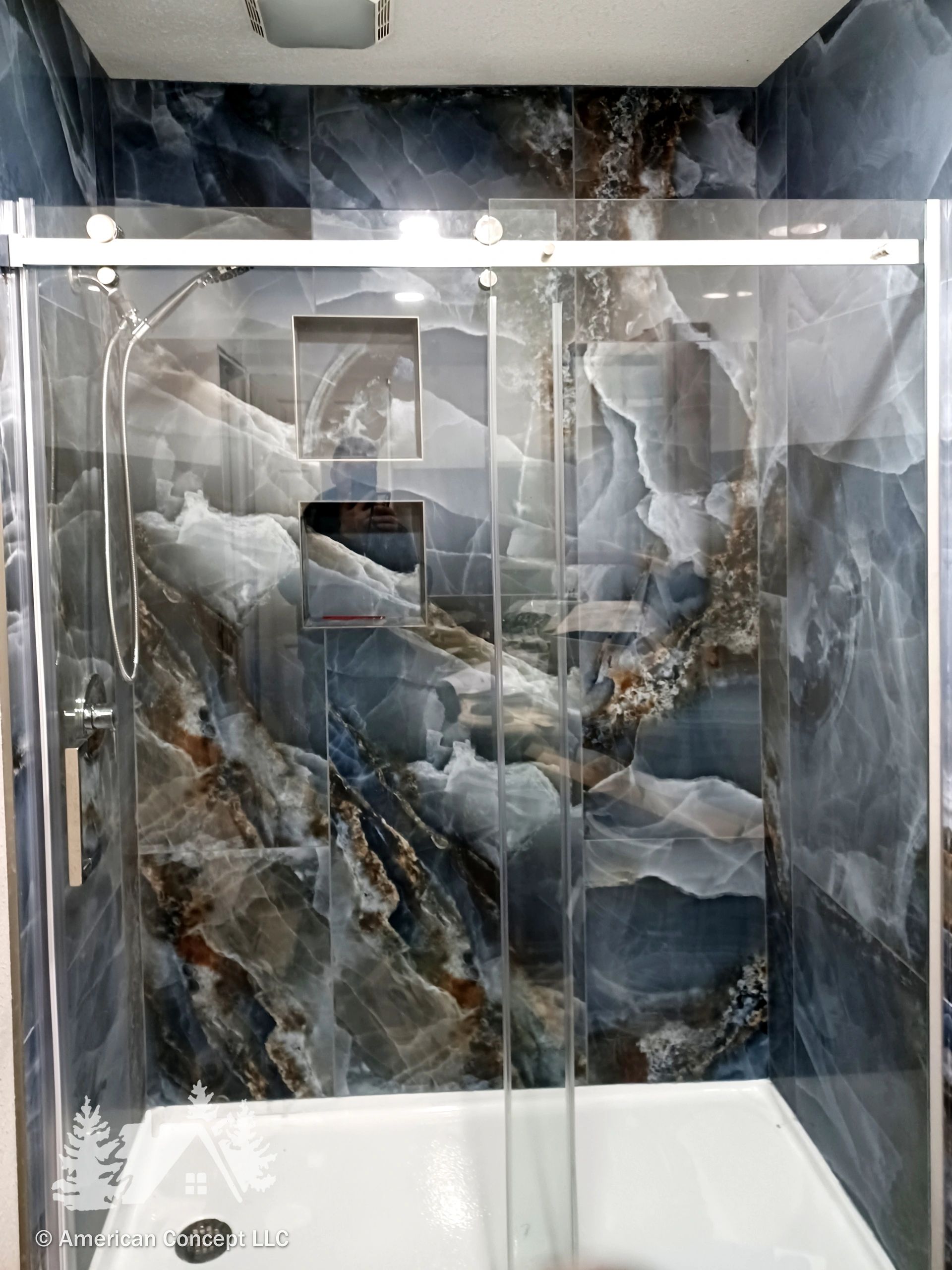 A custom shower with frameless sliding door and finished in Belize Azul polished porcelain tile.