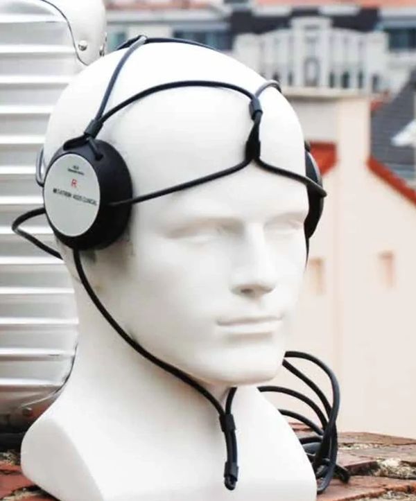 White mannequin head wearing vintage headphones with a unique strap design.