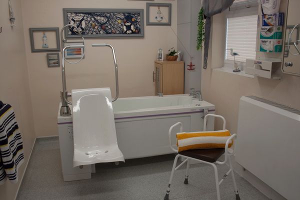 Bathroom equipped with accessibility aids like a shower chair and commode.