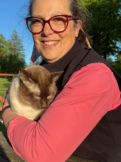 Woman holding a chocolate point Siamese