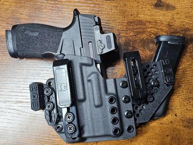 A handgun with a dual magazine holster on a wooden surface.