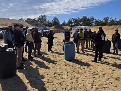 Group of people gathered outdoors on a sandy area.