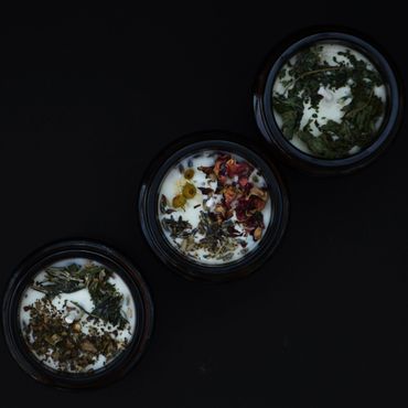 The tops of three small soy wax candles with dried herbs on top