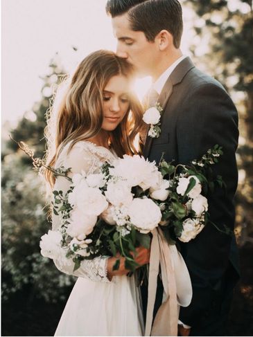 Bride and groom share an intimate moment with a beautiful bouquet.