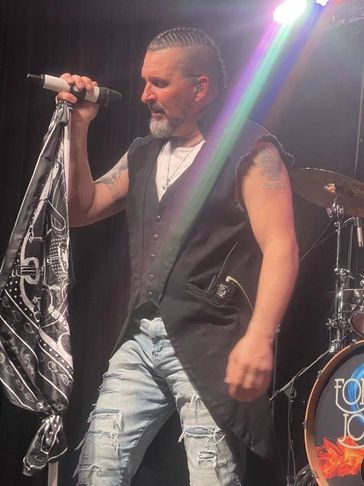Male singer performing on stage with microphone and bandana.