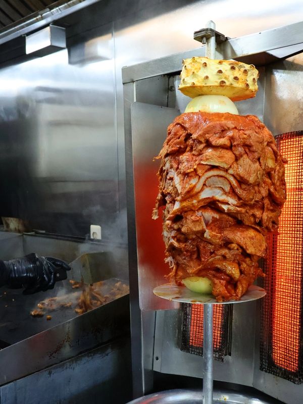 Meat roasting on a vertical spit for shawarma or tacos al pastor.
