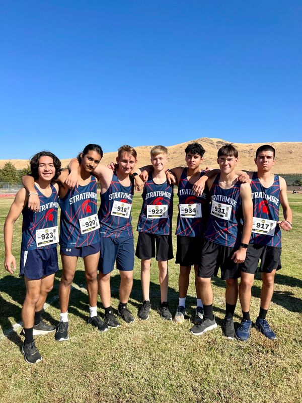 Seven Strathmore runners posing together outdoors on a sunny day.