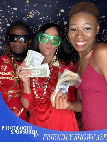Three people having fun with money in a photobooth.