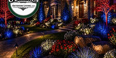 Beautifully lit garden pathway with vibrant flowers and colorful trees at night.