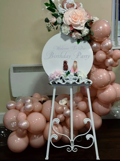 Pink and white balloon and crepe paper display board with welcome to our party written on