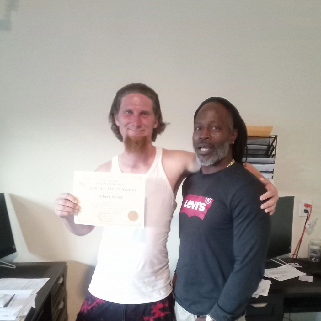 Two men smiling, one holding a certificate of award.