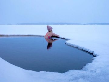 A lady embraces the cold water in an ice hole