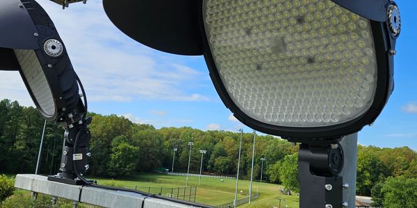 Close-up of stadium floodlights against a blue sky.