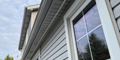 Side view of a house with a sliding door and window reflecting trees and a person.