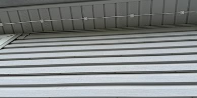Gray metal siding on a building with an overhanging roof and LED lights.