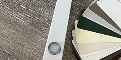 Color swatches and a white level tool on a wooden surface.