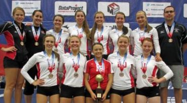 Smiling volleyball team posing with medals and a trophy.