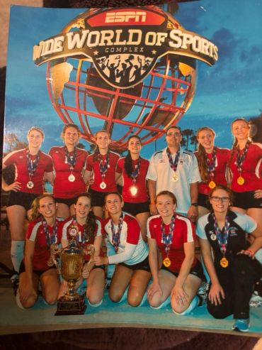 Volleyball team posing with medals and trophy at ESPN Wide World of Sports.