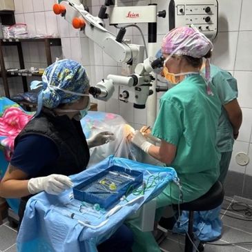 Surgeons performing a delicate eye surgery using a microscope in an operating room.